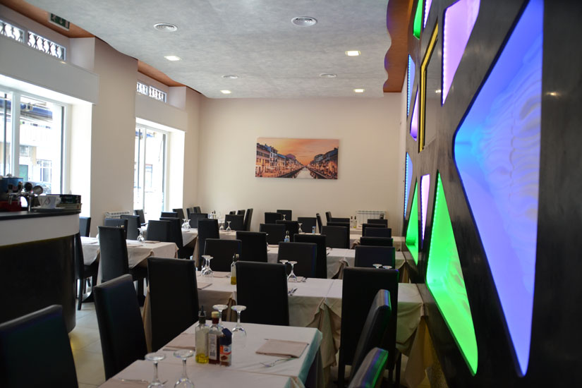 Sala interna del ristorante con tavoli e parete geometrica colorata