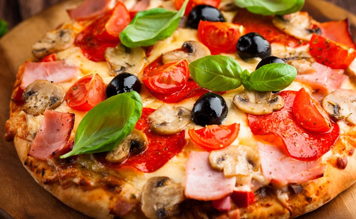 Pizza con prosciutto, funghi, pomodorini, olive e basilico – pizzeria con forno a legna